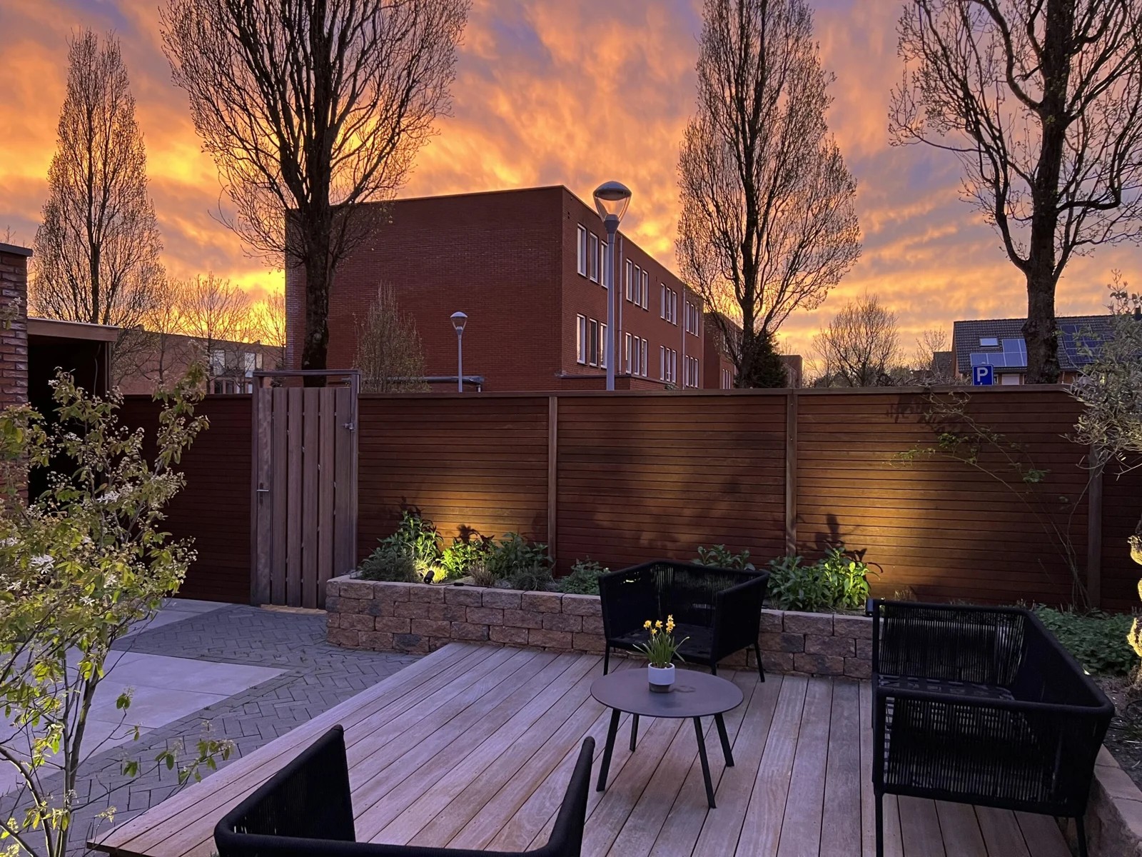 Tuin met sfeervolle verlichting langs de houten erfafscheiding